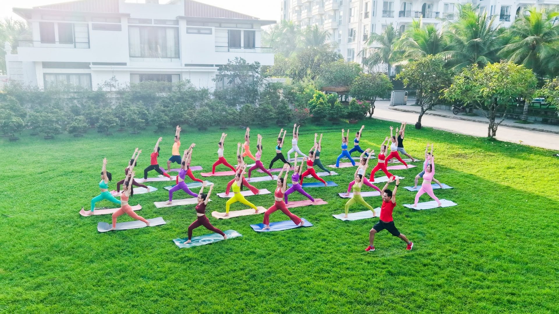 108 Tư Thế Yoga Chuẩn Định Tuyến — Khoá Học HLV Yoga Nào Cũng Nên Bắt Đầu 7 Chuyên gia Đặng Kim Ba hướng dẫn nhóm Huấn luyện viên Yoga tập định tuyến tư thế Chiến Binh trên sân cỏ ngoài trời tại Học viện Yoga T.Kim Việt Nam