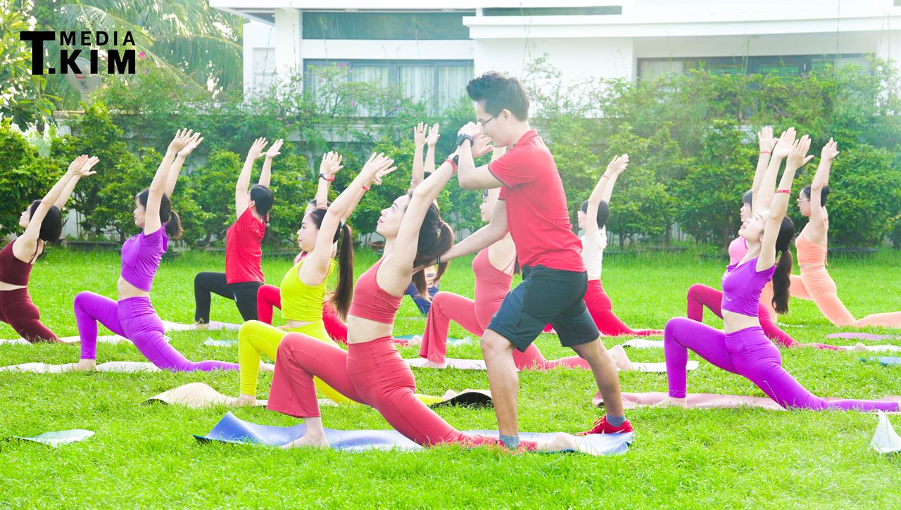 Yoga Buổi Sáng: Vì Sao Tập Sớm Tốt Cho Tim Mạch Hơn? Góc Nhìn Khoa Học 7 Lớp Yoga buổi sáng ngoài trời của Học viện Yoga T.Kim với đông học viên cùng tập trên thảm giữa sân cỏ