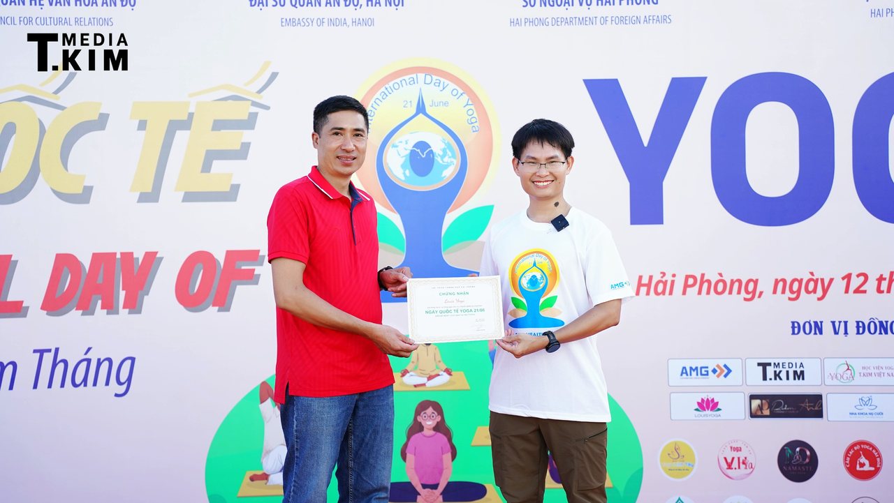 Tổng đạo diễn ở bàn cuối: người dựng cả buổi sáng Quốc tế Yoga Hải Phòng 2026 rồi lùi về sau ống kính 10 Đặng Kim Ba trao chứng nhận tài trợ cho Louis Yoga tại Quốc tế Yoga Hải Phòng 2026