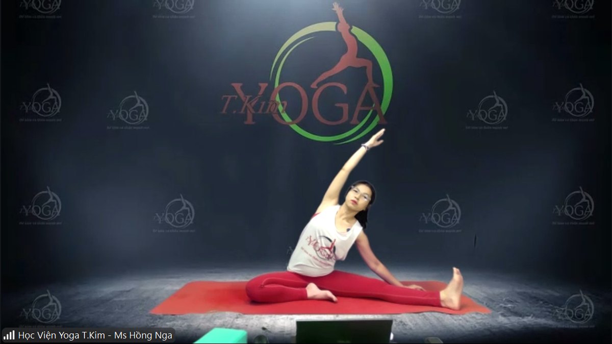 Huấn luyện viên Hồng Nga làm mẫu động tác nghiêng người kéo giãn eo lườn trong lớp Yoga Online qua Zoom của Học viện Yoga T.Kim